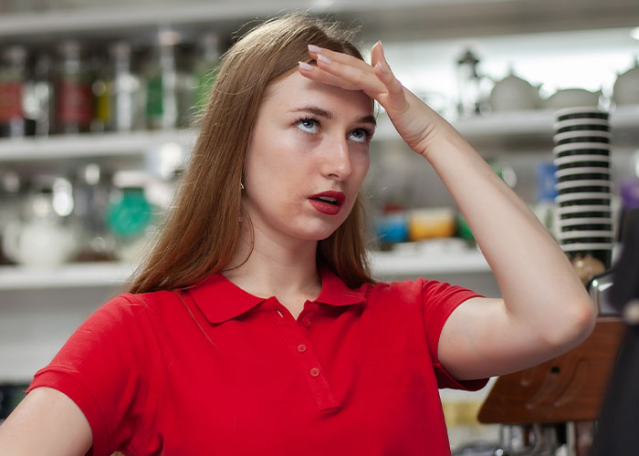 Young woman in red shirt rolling eyes, showing frustration after unhinged men comments about her looks in public.