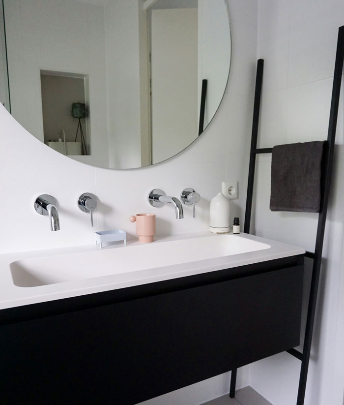 Modern bathroom sink with round mirror and towel rack illustrating surprisingly effective old wives' tales in home care.