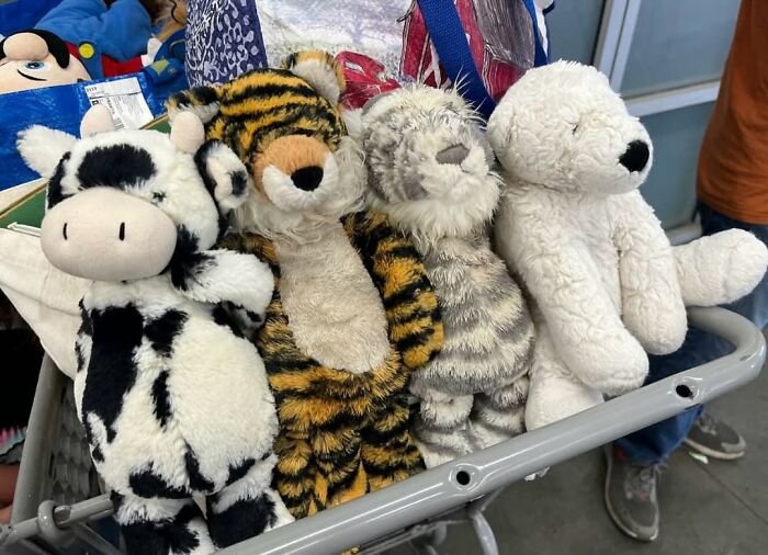 Plush animal toys including a cow, tiger, cat, and polar bear in a shopping cart, showcasing cool secondhand finds.