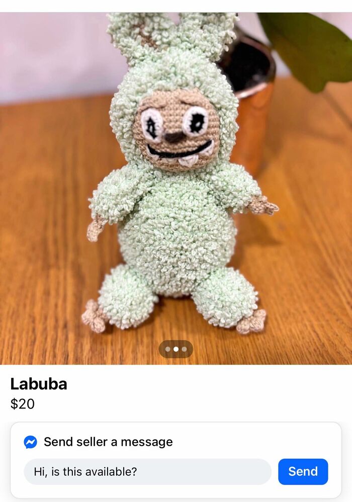 Crocheted DIY craft project of a green bunny with uneven facial features on a wooden table.