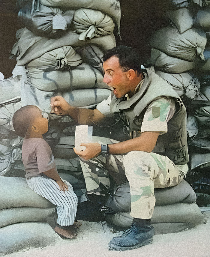 Soldier feeding a young child while sitting on sandbags, a rare historical photo capturing a compassionate moment during conflict.