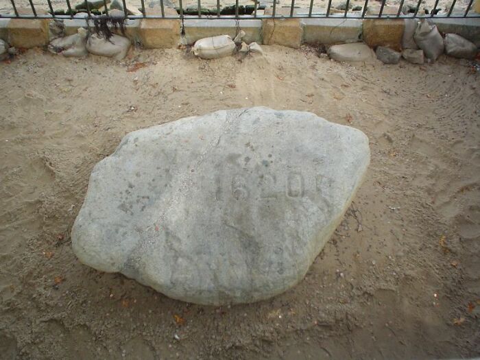 Large weathered stone with faded inscriptions on sand, symbolizing travel destinations that should be avoided by tourists.