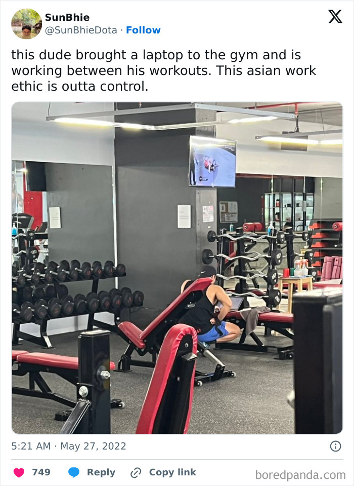 Man using a laptop between workouts in a gym filled with weights and benches, showcasing annoying gym moments.