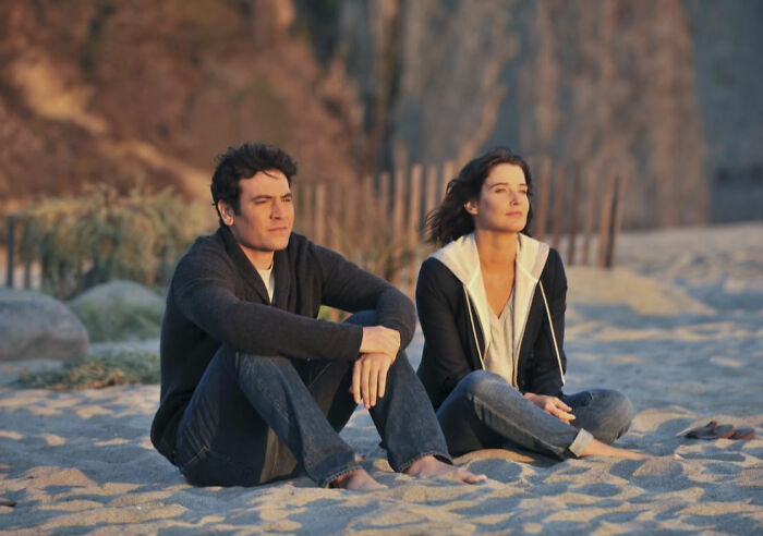 Couple sitting on the beach looking thoughtful, representing romantic but toxic movies inspired by The Notebook.