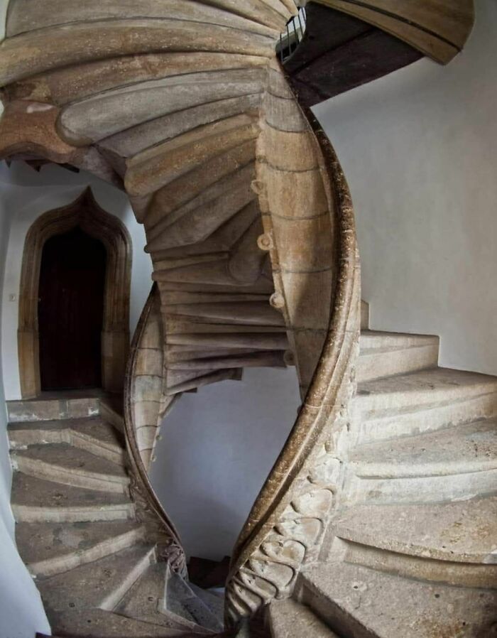 Spiral stone staircase with narrow steps and tight curves, showcasing a challenging death stairs design in an old building.