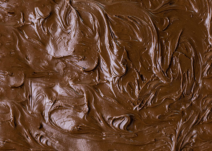 Close-up of smooth, swirled chocolate texture resembling dessert preparation at a buffet setting.