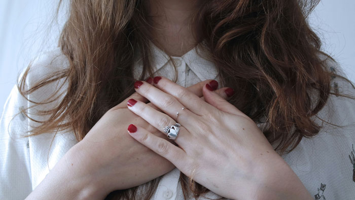 Woman with red nail polish holding hands over chest, symbolizing emotional revelations in therapy sessions