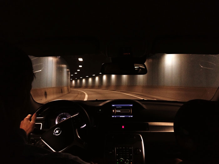 View from inside a car driving through a dimly lit tunnel, illustrating millennials reflecting on biggest lies told growing up.