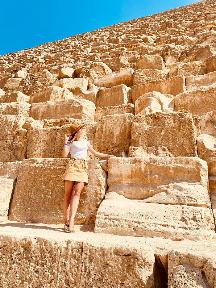 Woman in a hat standing by large stone blocks of an ancient pyramid under a clear blue sky for big no no travel tips