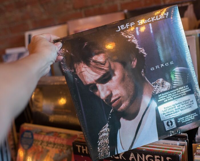 Person holding a vinyl record among albums, highlighting Nikola Tesla as an influential individual in history and innovation.