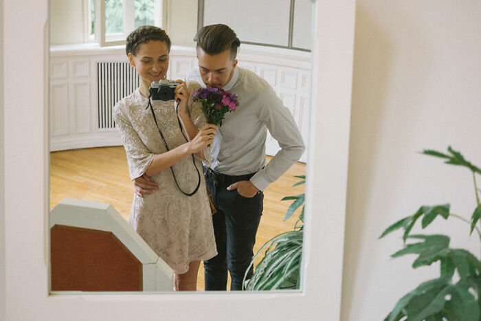 Couple taking a mirror selfie with flowers, capturing a heartfelt moment in their unforgettable wedding photos.