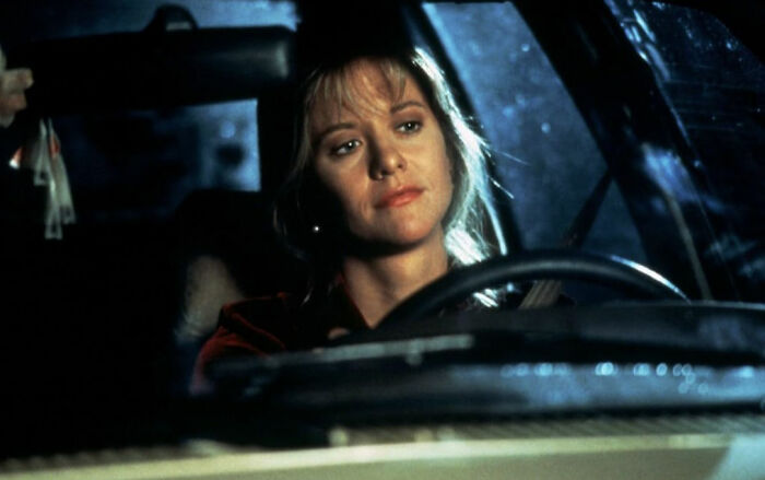Woman with a thoughtful expression driving a car at night, illustrating scenes from romantic but toxic movies.