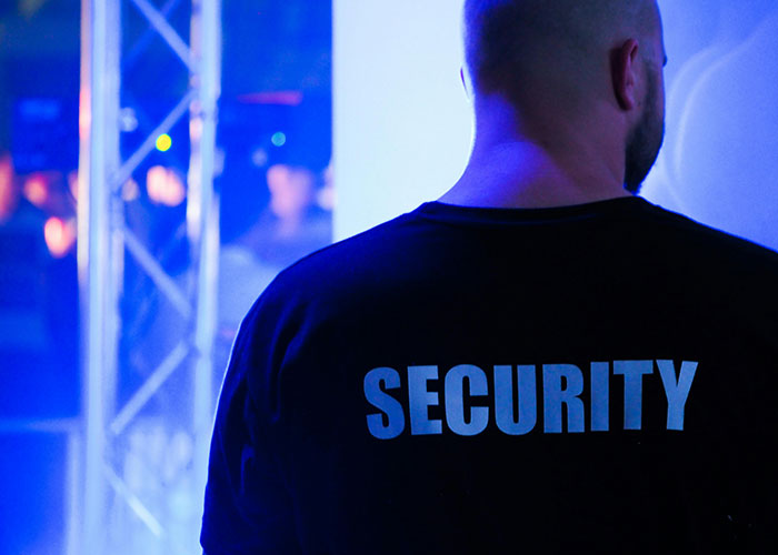 Security guard standing in a dimly lit event space representing a take one for the team moment in teamwork scenarios.