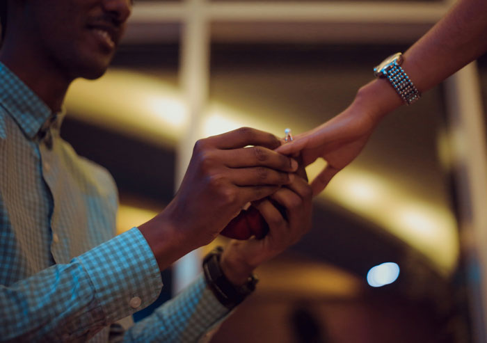 Man in a checkered shirt putting a ring on a woman's finger, highlighting toxic dating trends in relationships.