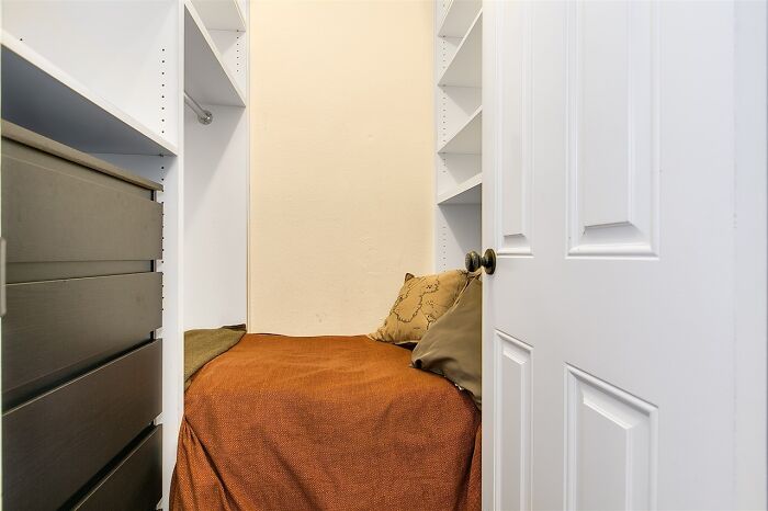 Small bedroom inside closet space with brown bedding and pillows, an example of unhinged real estate listings.