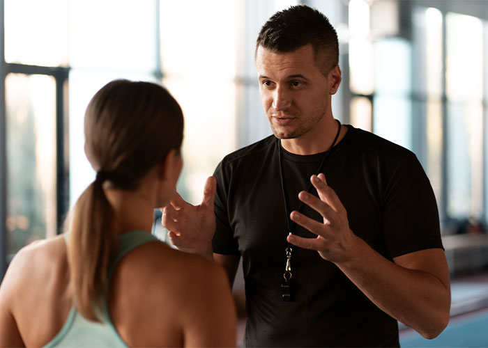 Man speaking intensely to a woman in a gym setting, illustrating unhinged things men have said about looks in public.