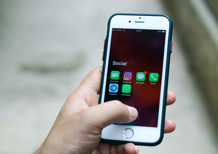 Hand holding smartphone displaying social media apps like Instagram and WhatsApp, illustrating biggest mistake of their lives concept.