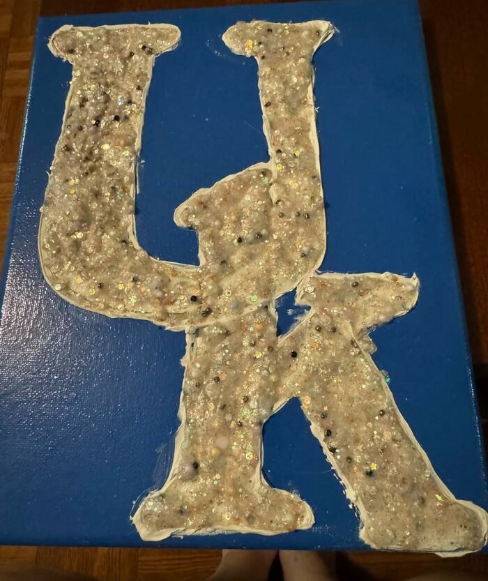 Craft showing poorly made glittery and uneven letters on a blue background, highlighting horrible crafts.