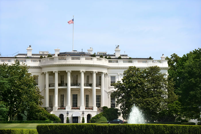 The White House exterior with American flag, fountain, and greenery illustrating millennials’ biggest lies growing up.
