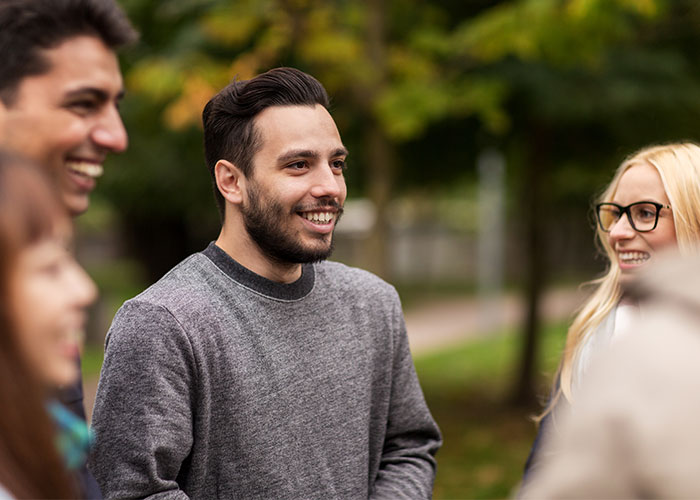 Group of people smiling and talking outdoors, sharing creepy facts that might get stuck in your brain forever.