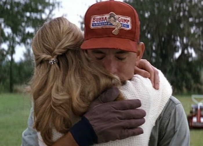 Man in red cap hugging woman with blonde hair outdoors, depicting a romantic but toxic movie scene from The Notebook context.