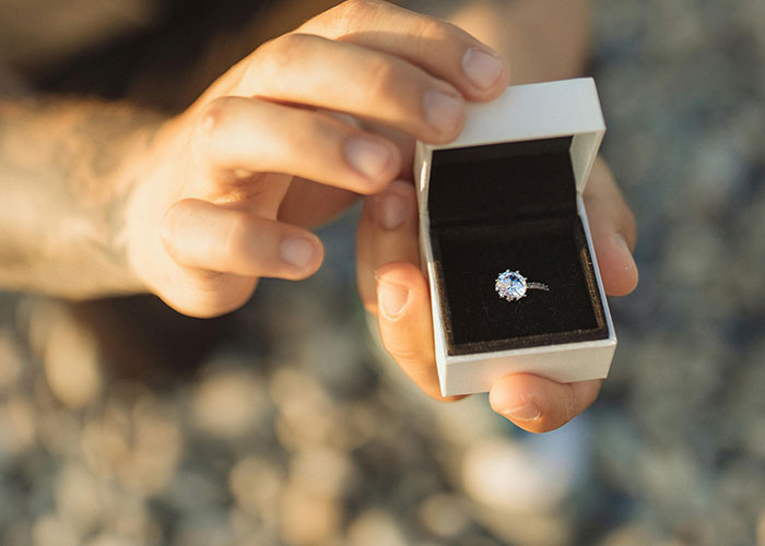 Close-up of hands holding an engagement ring box during an awkward date, highlighting painful and awkward moments on dates.