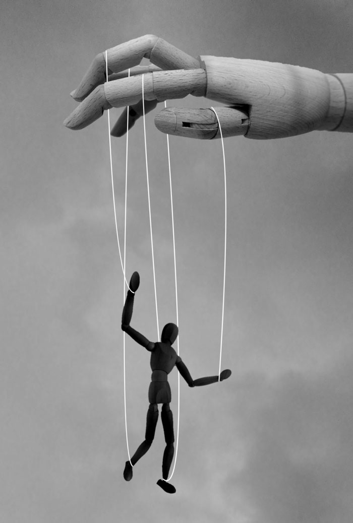 Wooden hand controlling a puppet with strings, symbolizing control and insane revelations in therapy sessions.