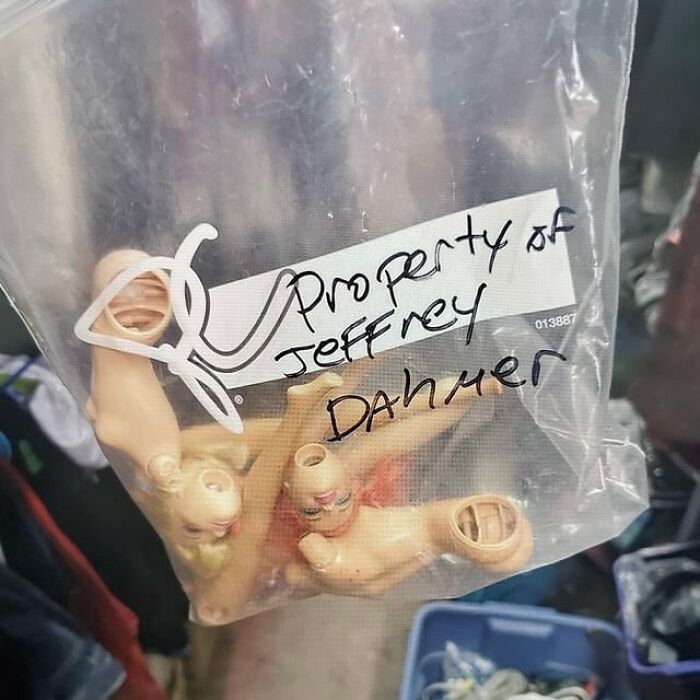Plastic bag with hand-lettered label and several small dismembered doll parts, showing unusual secondhand finds at a market.