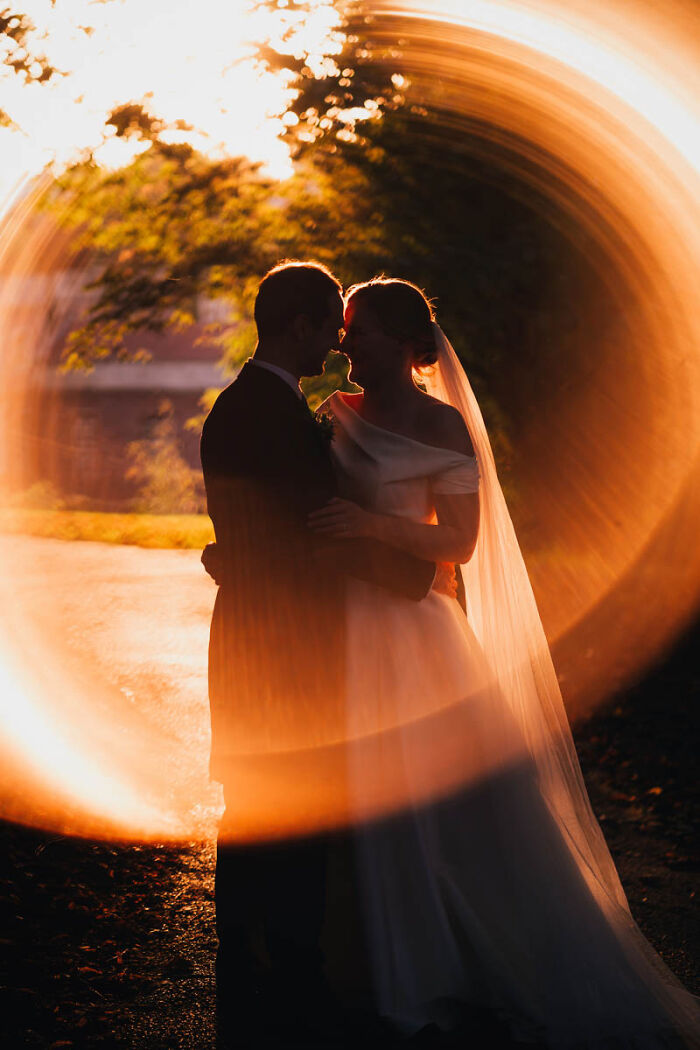 Bride and groom embracing during sunset with artistic light effects in unforgettable wedding photos collection.