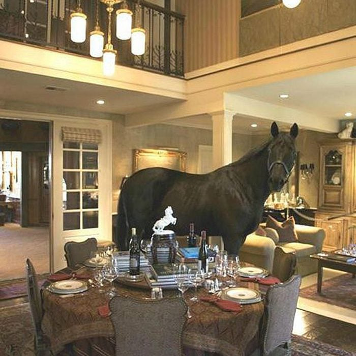 A horse standing inside an upscale dining room illustrating unhinged real estate listings with unusual decor choices.