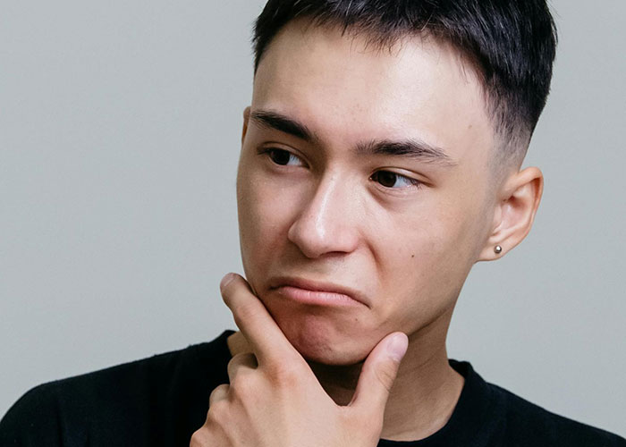 Young man with short dark hair, deep in thought, symbolizing a man planning revenge with a better ring proposal. Young man with short dark hair, deep in thought, symbolizing a man planning revenge with a better ring proposal.