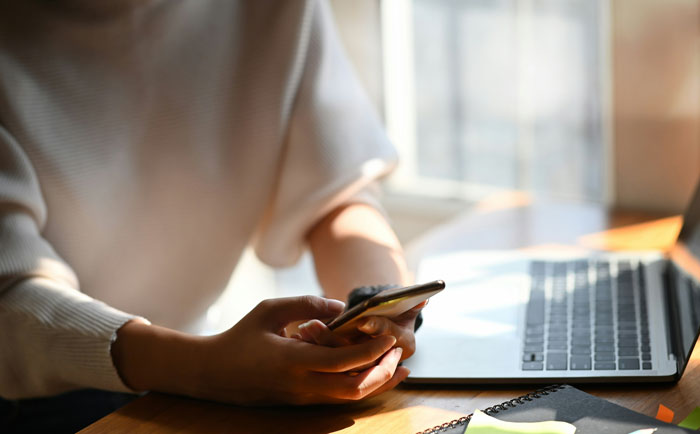 Freelancer working from home using smartphone and laptop, handling entitled church member demanding free work.