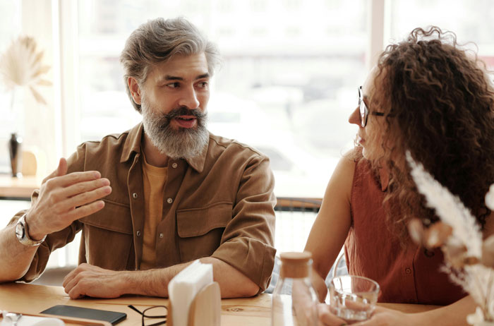 Middle-aged husband and wife having a serious conversation at a café, wife looking uncomfortable and grossed out. Middle-aged husband and wife having a serious conversation at a café, wife looking uncomfortable and grossed out.