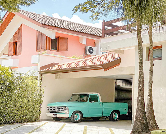 Vintage turquoise pickup truck parked in driveway of a suburban house, related to cheating boyfriend and woman confrontation.