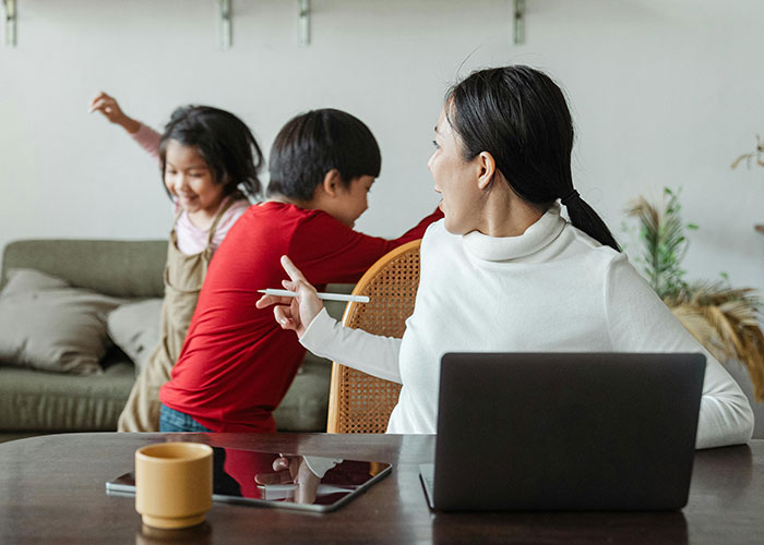 Mom assumes neighbor will babysit while she works on laptop, showing frustration after being declined in a home setting.