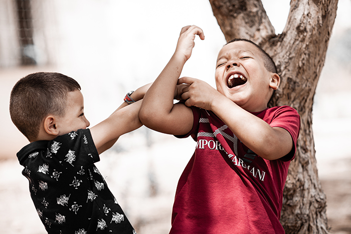Two young boys playfully wrestling outdoors, highlighting challenges in a blended family with a teen refusing responsibility.