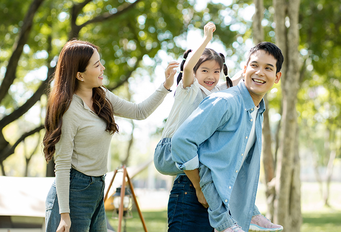 Family enjoying outdoor fun during China trip, highlighting bil struggles in a park with trees and sunlight.