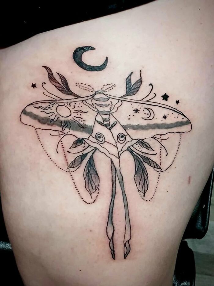 Tattoo of a moth with an abstract design featuring sun, moon, stars, and leaves inked on a person's back, showcasing a bad tattoo.