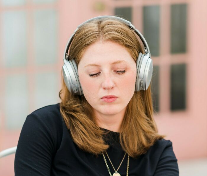 Woman over 42 wearing headphones, looking thoughtful and reflecting on what she’s no longer willing to tolerate.