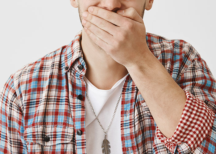 A man in a plaid shirt covering his mouth, expressing surprise inside the birthing room for the first time.