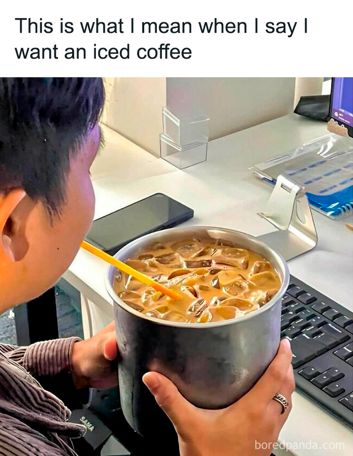 Person holding a large metal cup of iced coffee with a straw at a desk, relatable college confessions meme post.