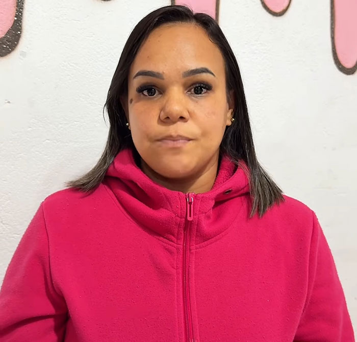 Woman in a pink jacket with serious expression, related to teen losing her life after eating cake with handwritten note.