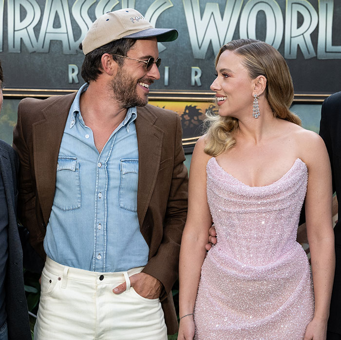 Scarlett Johansson in a sparkling pink dress smiling and posing with her costar at a movie premiere event.