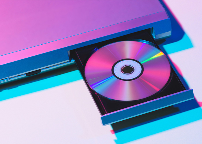 A laptop with an open disc drive holding a shiny disc, highlighting still use daily obsolete technology trends.