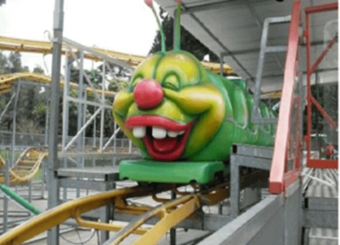 Green roller coaster with clown face at amusement park showing something normal that would shock most Americans