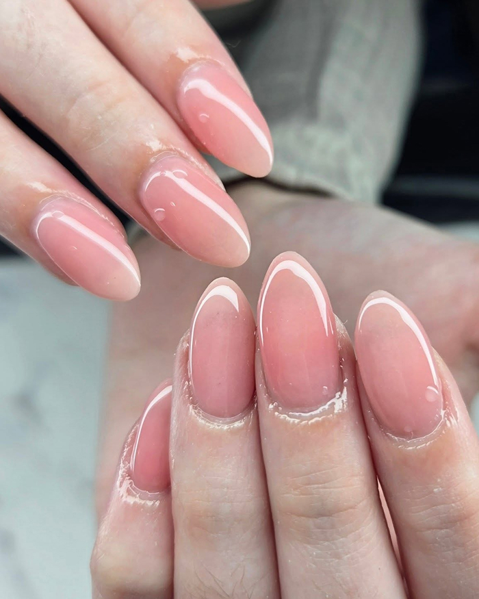 Glossy n**e gel nails on almond-shaped fingertips showcasing the hottest summer nails trend for 2025.