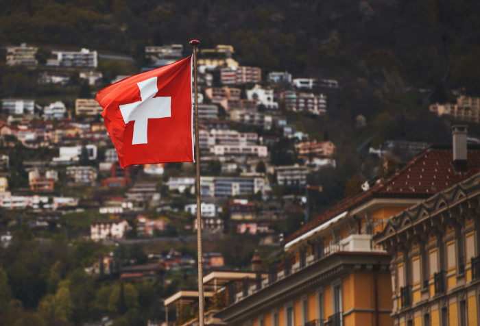 Swiss flag waving over a hillside town showcasing scenic views and urban living in one of the best countries to live in 2025.