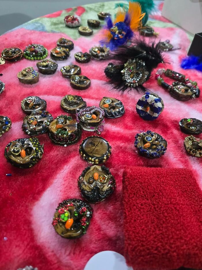 Assorted DIY craft projects with beads, feathers, and decorations on a colorful fabric, showcasing craft shaming examples.