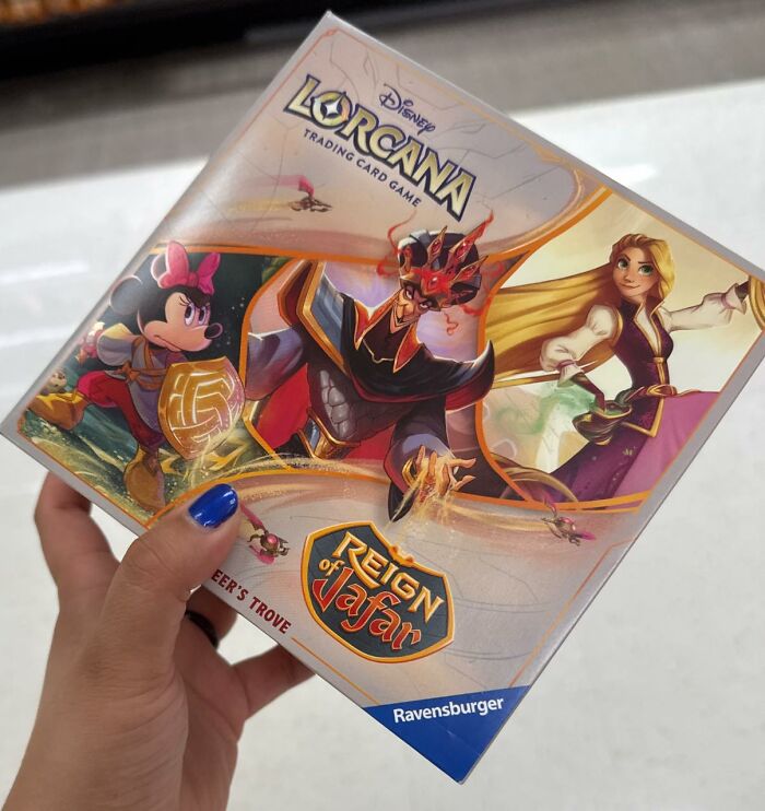 Hand holding Disney Lorcana trading card game box featuring Reign of Jafar with characters, popular in FB group.