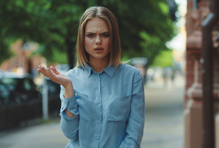 Young woman in a blue shirt looking confused outdoors, reflecting poor parenting concerns and potential custody issues.
